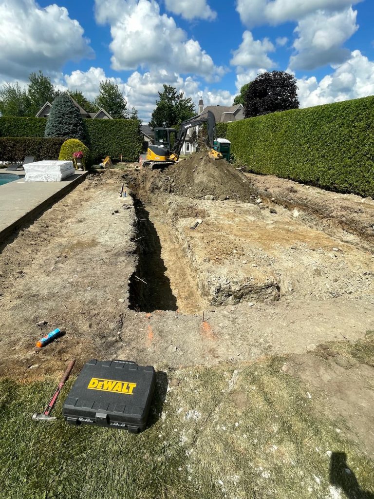 Tranchée réalisée par mini-excavatrice pour l’installation et la réparation de drains français en Estrie